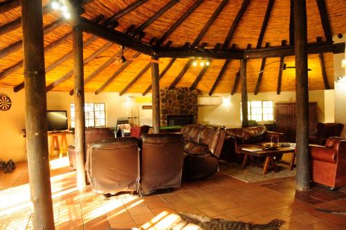 a living room with leather furniture and a wooden ceiling at Kruger Ranch in Magaliesburg