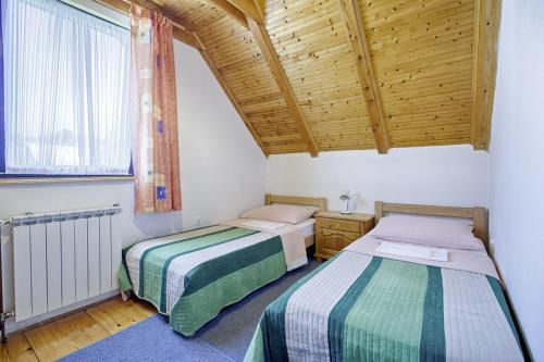 two beds in a room with a wooden ceiling at Milan in Rastovača (Haus für 5 Personen) in Rastovača