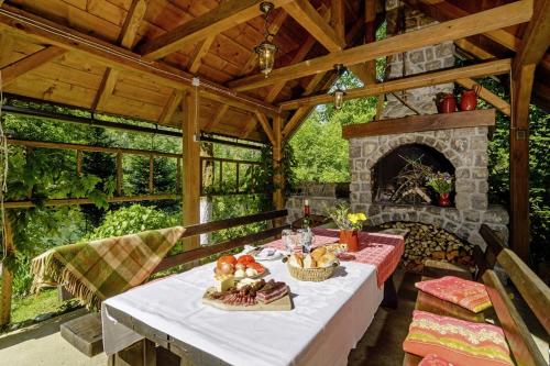an outdoor dining room with a table and a fireplace at Osmak in Gusti Laz (Haus für 4 Personen) in Brod na Kupi