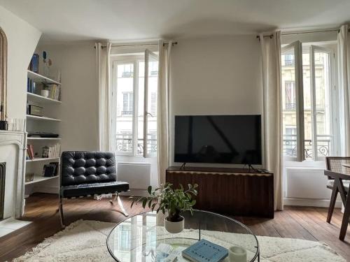 salon z telewizorem i szklanym stołem w obiekcie Why Paris ? Why Montmartre ? w Paryżu