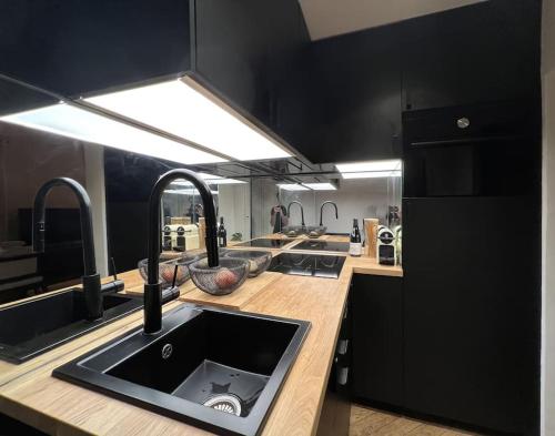 a kitchen with a sink and black cabinets at Why Paris ? Why Montmartre ? in Paris