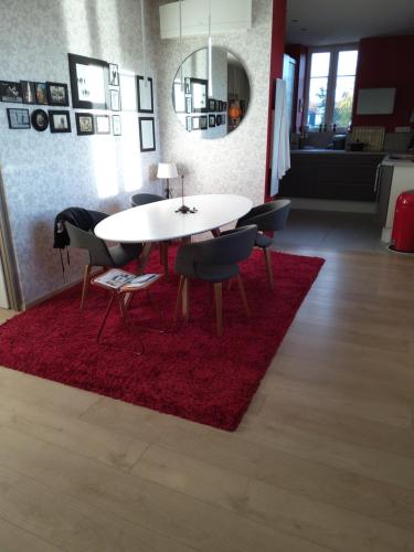 ein Esszimmer mit einem Tisch und Stühlen auf einem roten Teppich in der Unterkunft Le jardin des roses in Colmar