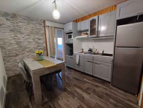 a kitchen with a table and a stainless steel refrigerator at Superbe Loft cocooning in Ustou