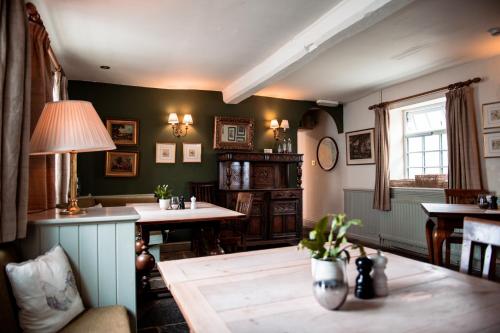 a living room with green walls and tables and a lamp at The Wellington Heifer in Northallerton