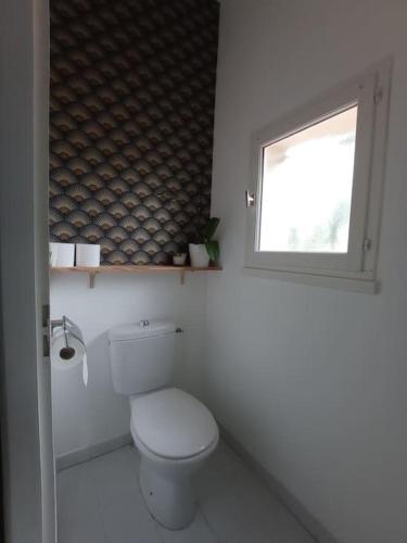 une salle de bain blanche avec toilettes et fenêtre dans l'établissement Agréable maison piscine chauffée et spa à Andernos, à Andernos-les-Bains