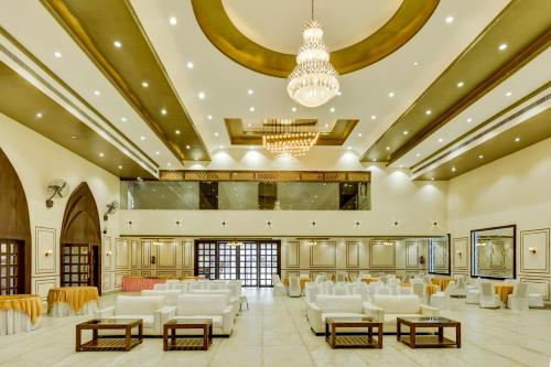 a large banquet hall with white chairs and a chandelier at Treebo Winsome Banquet And Resort in Rānchī