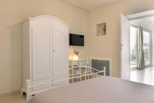a white bedroom with a bed and a tv on the wall at Tenuta Traghetto in Ostuni