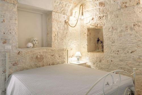 una camera con letto e parete in pietra di Tenuta Traghetto a Ostuni