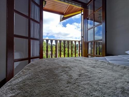 a bedroom with a large window and a large bed at Pousada Campos de Paiva in Campos do Jordão