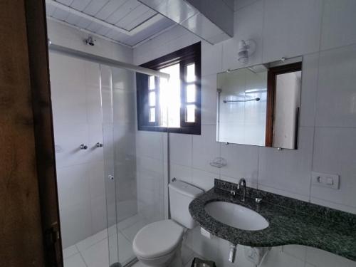 y baño con aseo, lavabo y espejo. en Pousada Campos de Paiva, en Campos do Jordão