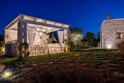 a home with a lit up backyard at night at Tenuta Traghetto in Ostuni