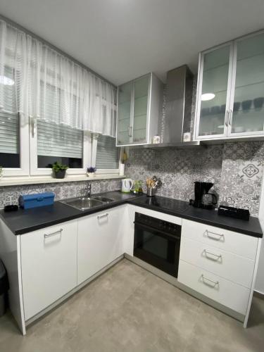 a kitchen with white cabinets and a black counter top at Apartman NADA in Slavonski Brod