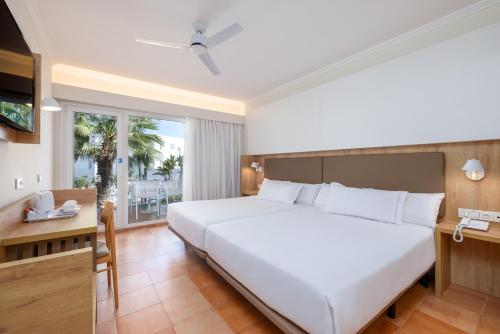 a bedroom with a large white bed and a desk at Playaballena in Costa Ballena