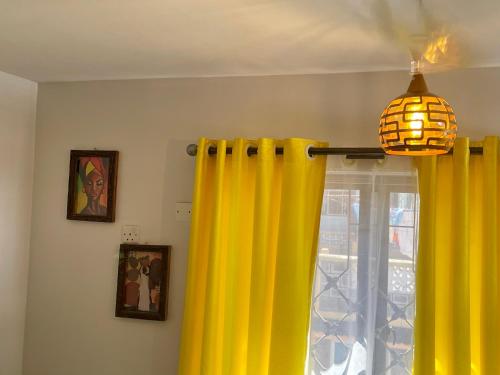 a room with yellow curtains and a chandelier at Unique apartment in Mombasa