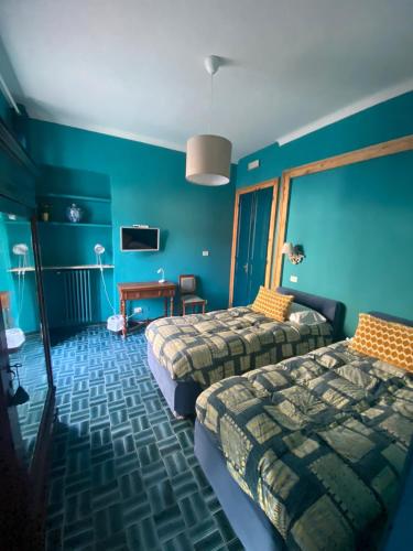 Cette chambre bleue comprend 2 lits et une table. dans l'établissement Albergo Bergagna, à Pont Canavese