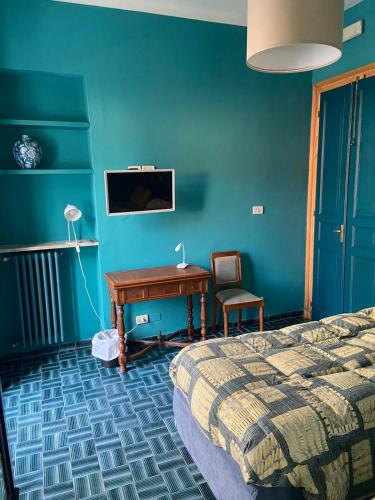 a bedroom with a desk and a bed and blue walls at Albergo Bergagna in Pont Canavese