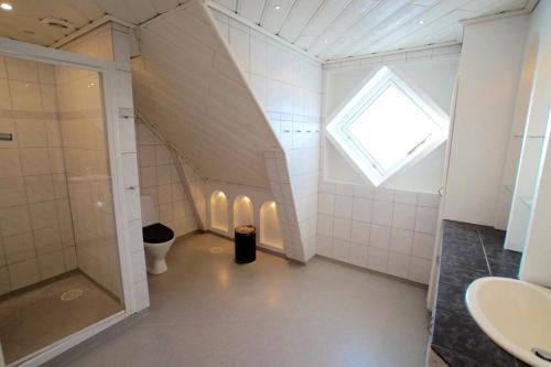 a bathroom with a shower and a toilet and a window at Skagen Villa & Apartments in Skagen