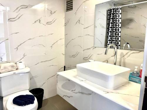 a white bathroom with a sink and a toilet at Patong Beach Gardens - Pool Fast WiFi Smart TVs in Patong Beach