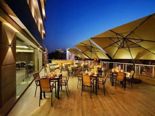 ein Restaurant mit Tischen, Stühlen und Sonnenschirmen in der Unterkunft Hotel Suba Elite Vadodara in Vadodara