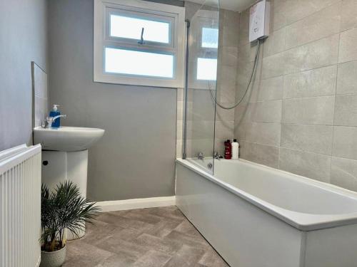 een badkamer met een bad, een wastafel en een raam bij Three Bedroom House Next to Brighton Station slp 9 in Brighton & Hove