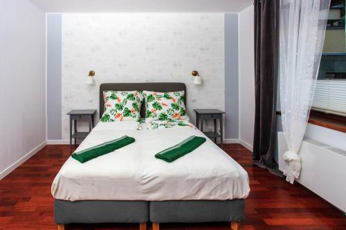 a bedroom with a bed with two green pillows at Comfy Apartment Dobra 54 in Warsaw