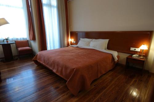 a hotel room with a large bed and wooden floors at Hotel Excelsior in Loutraki