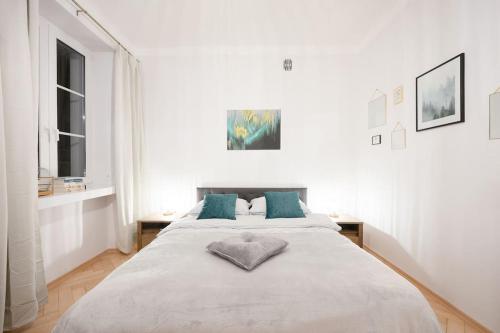 a white bedroom with a large bed with blue pillows at Apartamenty - MI Forest in Warsaw