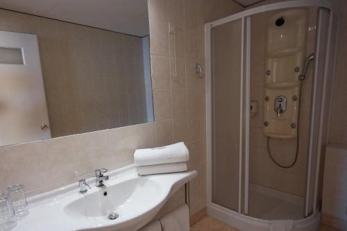 y baño con lavabo y ducha con espejo. en Hotel Excelsior, en Loutraki