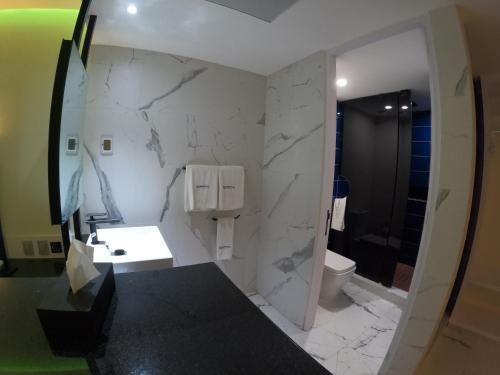 baño con pared de mármol blanco en WeEnjoy Hotels Grand Prix Aeropuerto CDMX en Ciudad de México