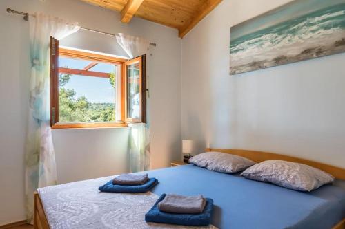 a bedroom with a bed with blue sheets and a window at beautiful bay house Duga in Okrug Gornji