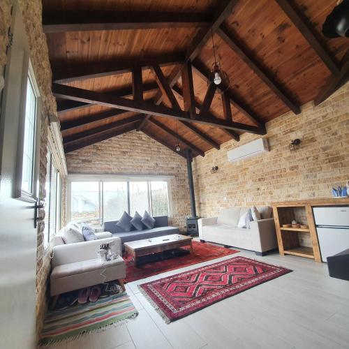 a living room with white couches and a brick wall at Al baidar zimmer in Mas'ade