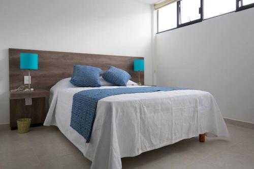 a bedroom with a bed with blue pillows on it at JUUB More Oaxaca Impossible (R1) in Oaxaca City