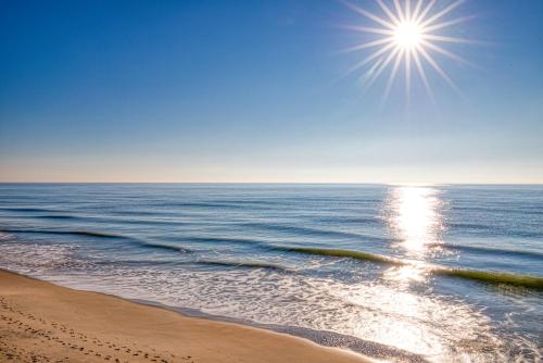 una playa con el sol brillando sobre el océano en Topsail Dunes, en North Topsail Beach