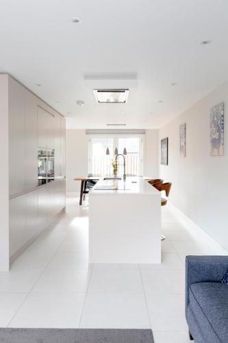 a white kitchen with a sink and a couch at Fabulous Central Windsor Town House With Parking in Windsor