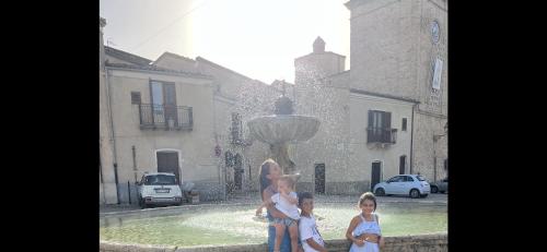 a woman and three children standing in front of a fountain at Villetta con Oliveto CFG in Prizzi