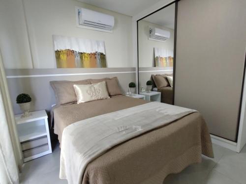 1 dormitorio con 1 cama grande y espejo en Mariscal, 03 dormitórios, 80m do mar, com piscina, en Bombinhas