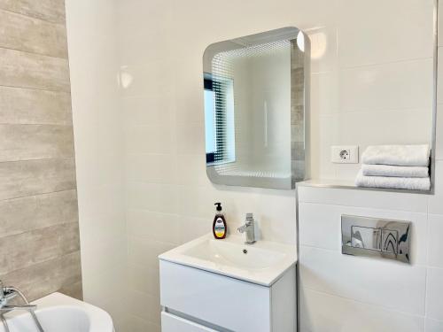 bagno bianco con lavandino e specchio di Luxury apartments a Suceava