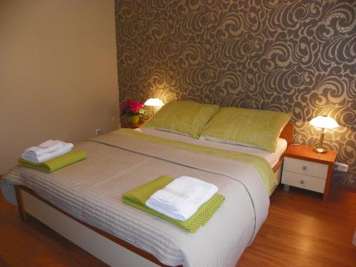 a bedroom with a bed with green towels on it at Centrum Panzió in Mohács