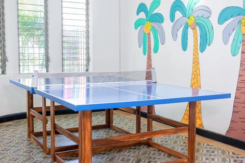 een tafeltennistafel met een blauwe top en palmbomen aan de muur bij Puerta Aqua by La Puerta Hostels in Santa Marta