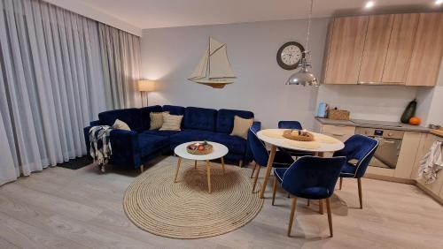 a living room with a blue couch and a table at Zielony Domek Apartament w Rewalu 42 m2, tylko 40 metrów od plaży in Rewal