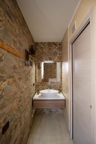a bathroom with a sink and a stone wall at Kleosuite Iris Opera Ortigia in Syracuse