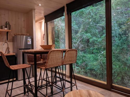 a kitchen with a table and chairs in front of a window at Refugios Outscape Fuy, Huilo Huilo in Puerto Fuy