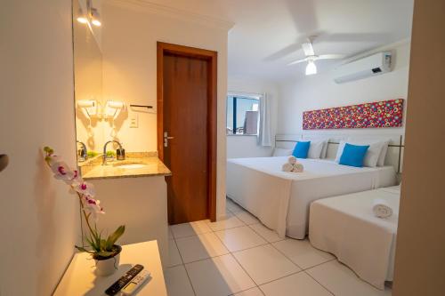 a room with two beds and a bathroom with a sink at DUPLEX 2 SUÍTES CONDOMÍNIO MONT CARMELO in Porto Seguro