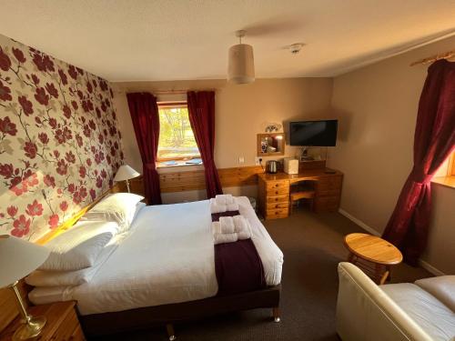 una camera con letto, scrivania e TV di Smithton Hotel a Inverness