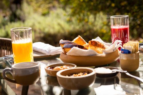 a table with a bowl of bread and two glasses of juice at Pousada Boutique Figueira da Serra in Campos do Jordão