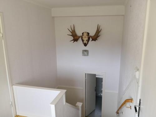 a stairway with a deer head hanging on the wall at Gula huset, Lakene Ostgård in Lakene