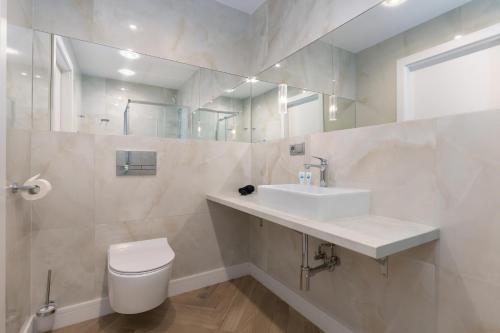 a bathroom with a sink and a toilet and a mirror at Aparthotel Etna in Kołobrzeg