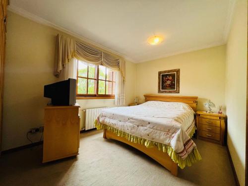 1 dormitorio con 1 cama y TV en MRG- Colonial 2D - 200 mts da Rua Torta, en Gramado