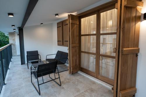 a room with chairs and wooden doors on a balcony at Palazzino Luxury Suites in Lofou