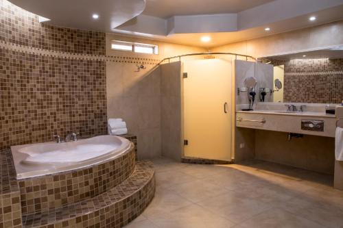 a bathroom with a large tub and a sink at Hotel Santorian in Hermosillo